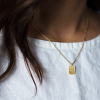 gold mini tag necklace on model